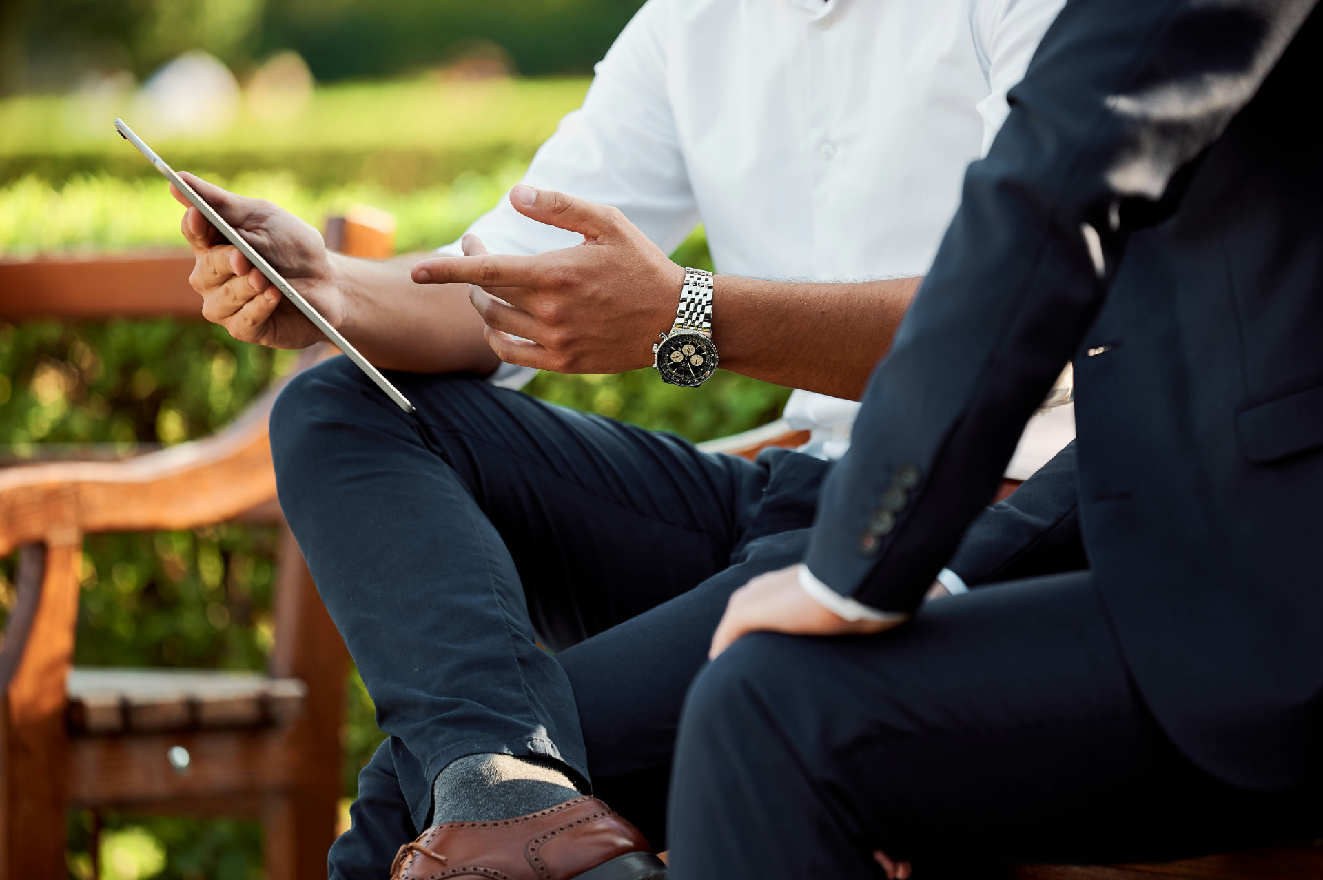 Two business professionals meeting outdoors and discussing business over a tablet